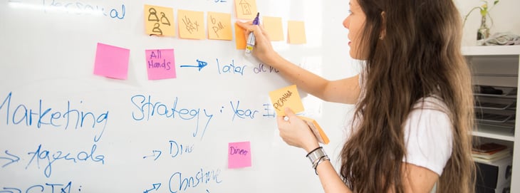 A marketer conducting a competitive analysis on a whiteboard.