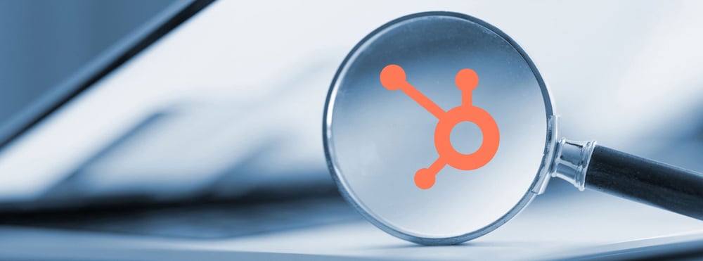 Close-up photograph of a magnifying glass highlighting the HubSpot icon.